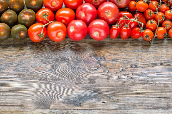 Colorful tomatoes on wooden table background. Top view. — Stock Photo, Image