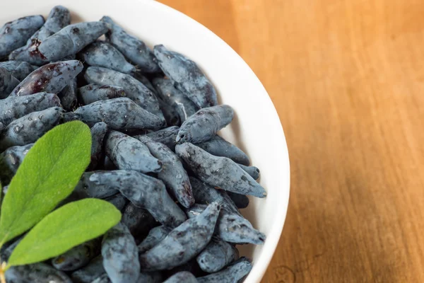 Rijpe kamperfoelie (lonicera) in de kom op een houten tafel. — Stockfoto