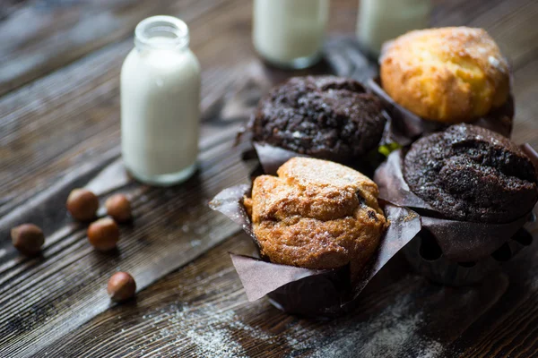 White milk and chocolate baked muffins on wooden table.