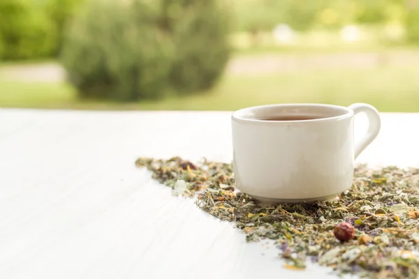 Taza de té en la mesa con hierbas —  Fotos de Stock