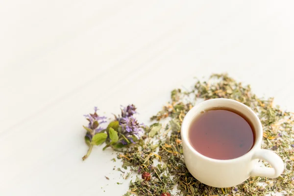 Taza de té en la mesa con hierbas —  Fotos de Stock