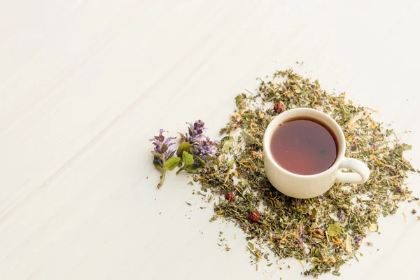 Taza de té en la mesa con hierbas —  Fotos de Stock