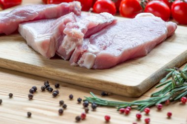 Kesme tahtasında çiğ domuz eti ve sebze.