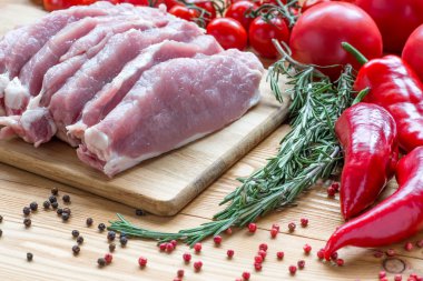 Kesme tahtasında çiğ domuz eti ve sebze.