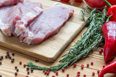 Kesme tahtasında çiğ domuz eti ve sebze.