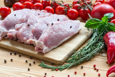 Kesme tahtasında çiğ domuz eti ve sebze.