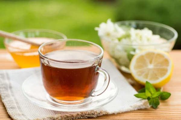 Té de hierbas en una taza con y miel, jardín de verano —  Fotos de Stock