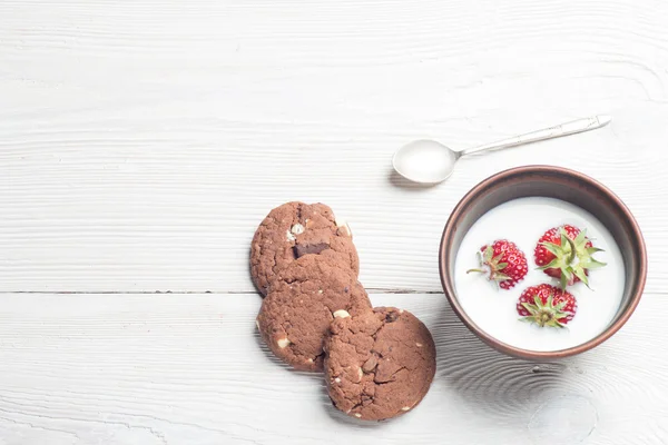 Fresas frescas en tazón con galletas sobre mesa de madera blanca —  Fotos de Stock