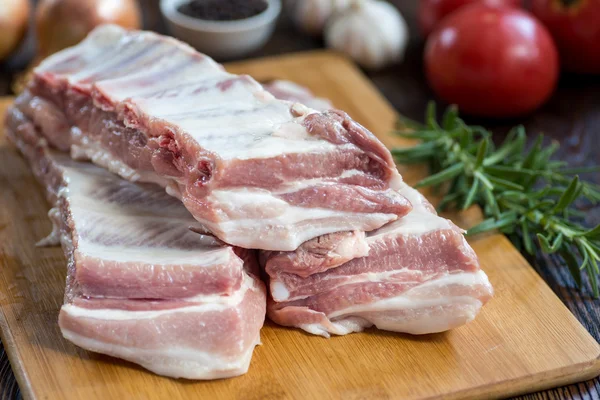 Feche a carne crua de porco na placa de madeira com um frasco de especiarias — Fotografia de Stock