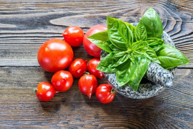 Taze olgun domatesler ve ahşap masada fesleğen..