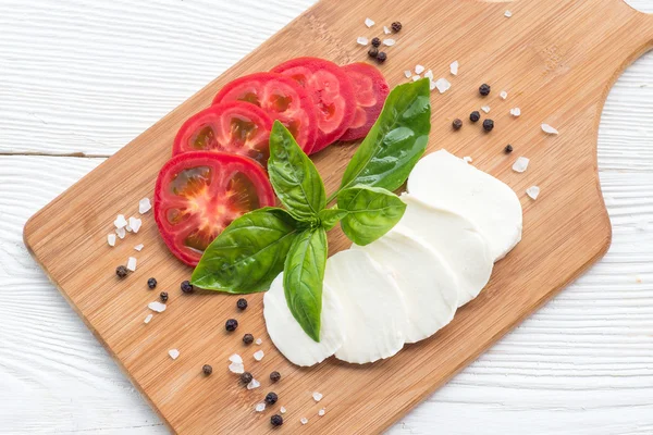 Mozzarella, tomater och färsk basilika blad på skärbräda — Stockfoto