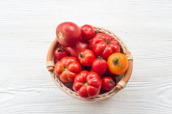 Fresh red tomatoes in a basket on a white background — Stock Photo, Image