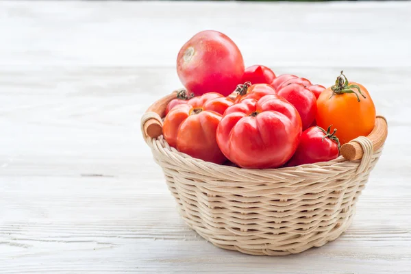 Fresh red tomatoes in a basket on a white background — Stock Photo, Image