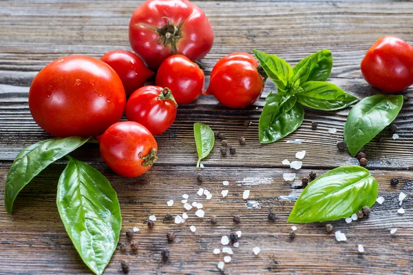 Tomatoes with basil in colander on wooden table background. Food — Stock Photo, Image