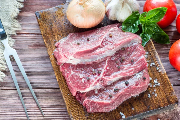 Bife cru em uma mesa de madeira escura. — Fotografia de Stock