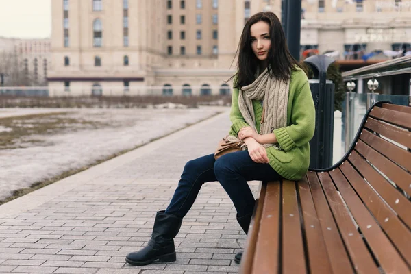 Όμορφη σύγχρονη γυναίκα με μακριά καστανά μαλλιά, κάθεται σε παγκάκι — Φωτογραφία Αρχείου