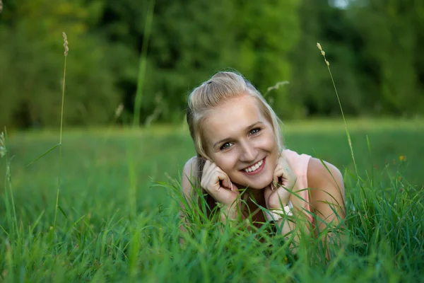 Une jeune femme joyeuse et rieuse allongée sur l'herbe — Photo