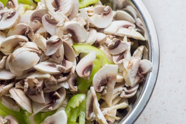 Metalik bir tabak içinde dilimlenmiş champignon mantar ve yeşil biber