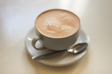 Hafif bir arka plan üzerinde beyaz bir fincan CAPUCINO veya sütlü kahve