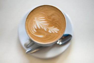 Hafif bir arka plan üzerinde beyaz bir fincan CAPUCINO veya sütlü kahve