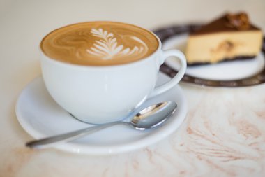 Beyaz bir bardakta bir pasta ile CAPUCINO veya sütlü kahve