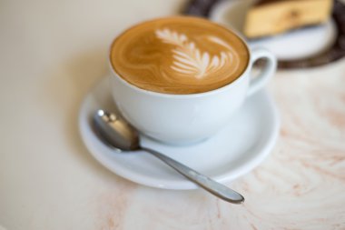 Beyaz bir bardakta bir pasta ile CAPUCINO veya sütlü kahve