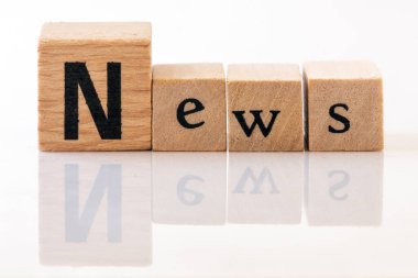 Gri arkaplandaki ahşap harflerden dizilmiş NEWS metni