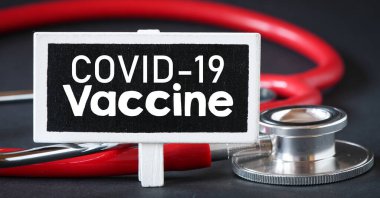 COVID-19 aşı metni steteskopun yanındaki küçük bir karatahtaya yazılmış.. 
