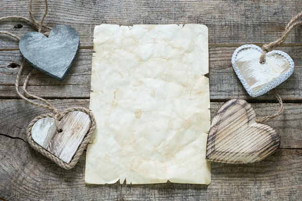 Corazones de madera con hoja de papel vieja — Foto de Stock