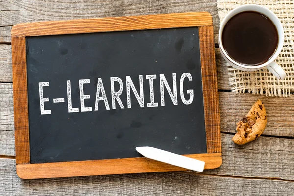 Blackboard with text "E-learning" on old wooden table — Stock Photo, Image