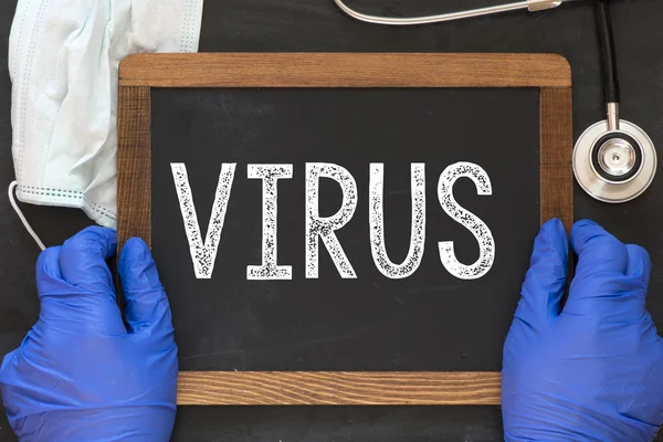 Medico in possesso di lavagna con la parola virus — Foto Stock