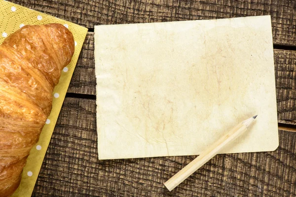 Croissant saboroso e papel — Fotografia de Stock