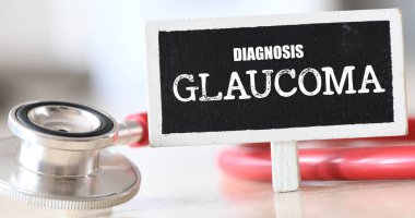 Steteskopun yanında küçük bir tebeşir tahtasında GLAUCOMA kelimesi.