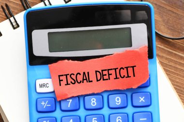 FISCAL DEFICIT sözcükleri bir hesap makinesi üzerine yerleştirilmiş kırmızı kağıt parçası.