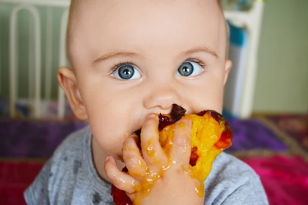 Pequeño niño dulce comiendo un melocotón — Foto de Stock