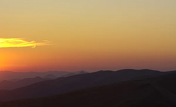 Silhuetas de cumes de montanha à luz do sol nascente — Fotografia de Stock