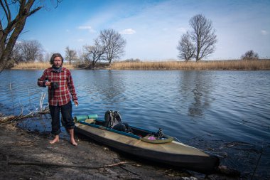 Kayığın yanındaki kıyıda duran adam.