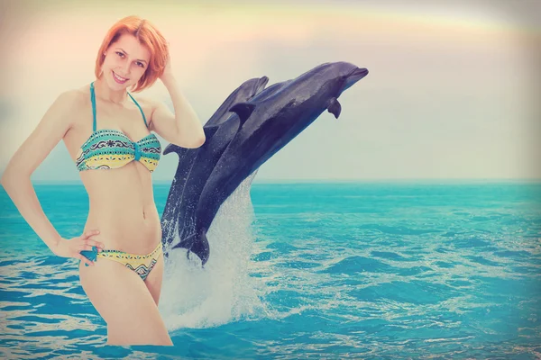 Girl on the beach with dolphins — Stock Photo, Image