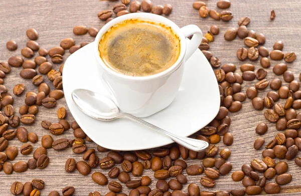 Cup of coffee and coffee beans on wooden table — Stock Photo, Image