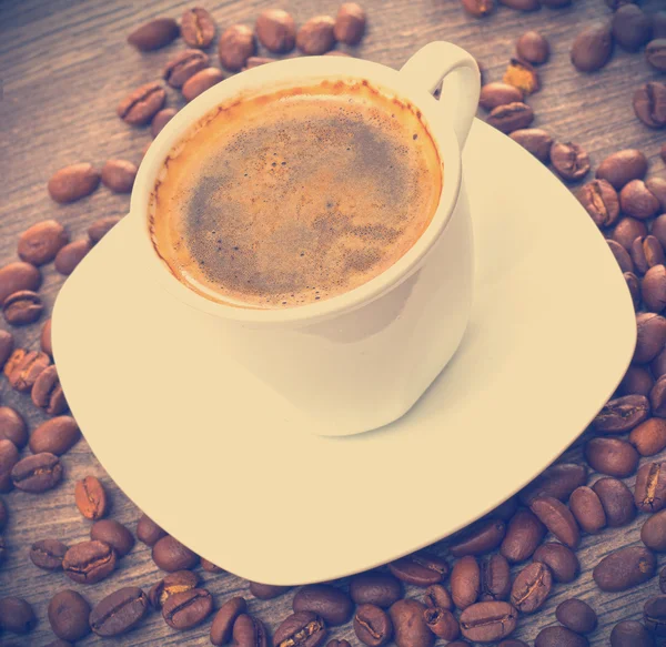 Cup of coffee and coffee beans on wooden background — Stock Photo, Image