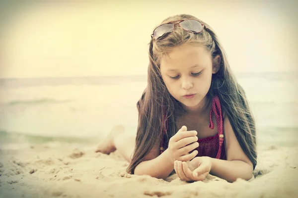 Meisje spelen met zand op het strand — Stockfoto