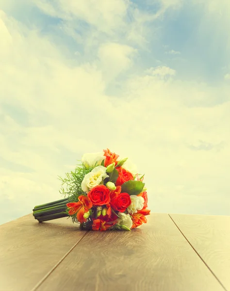 Ramo de flores sobre una mesa de madera sobre un fondo del cielo — Foto de Stock