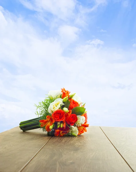 Mazzo di fiori su un tavolo di legno su uno sfondo di cielo — Foto Stock