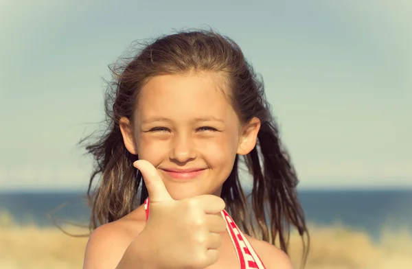 Ребенок показывает большой палец на фоне моря — стоковое фото