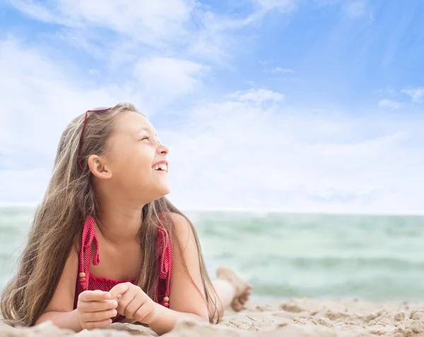 Vacker liten flicka ligger på den sandiga stranden — Stockfoto