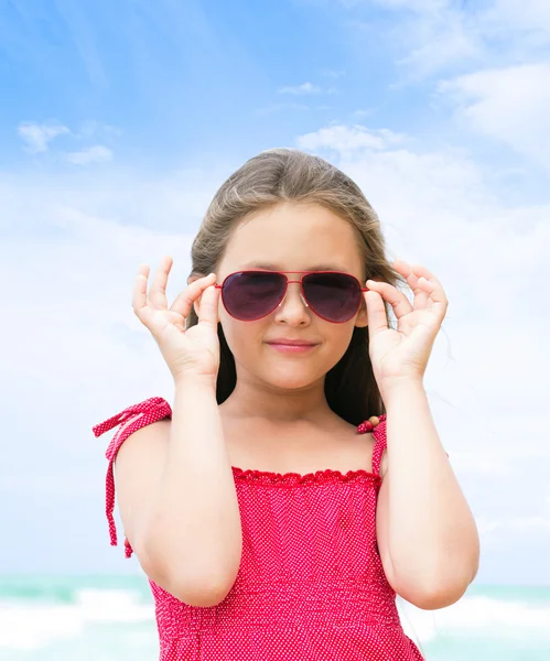 Portrait of a little girl in sunglasses on the beach — Stock Photo, Image
