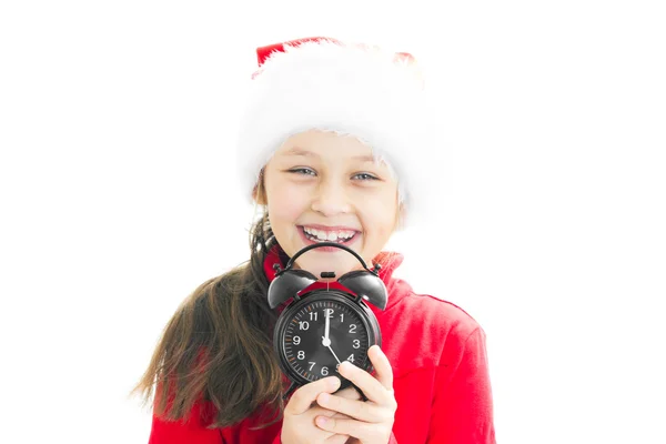 Little girl in Santa Claus hat holding alarm clock showing twelv — Stock Photo, Image