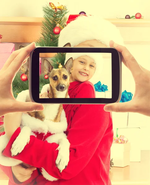Niño en ropa de Navidad sosteniendo a su perro y posando para un fot —  Fotos de Stock