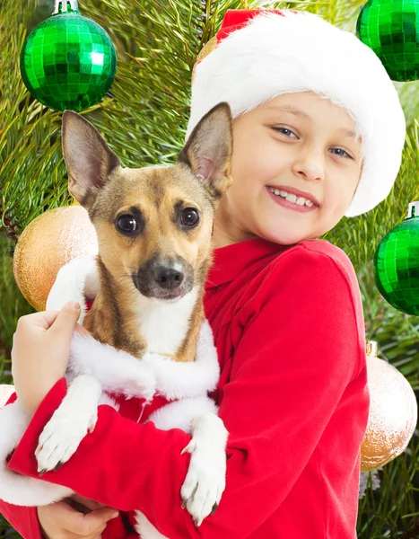 Encantador niño en ropa de Navidad sosteniendo a su perro — Foto de Stock