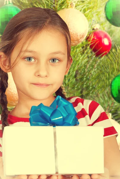 Cute kid holding a box with Christmas present on background of N — Stock Photo, Image